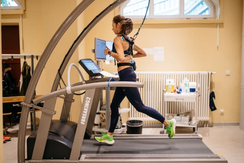 Žena běží na běžícím pásu s připojenými senzory pro měření VO2max.