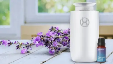 Bílý difuzér s esenciálními oleji a fialová lavanda na dřevěném stole.