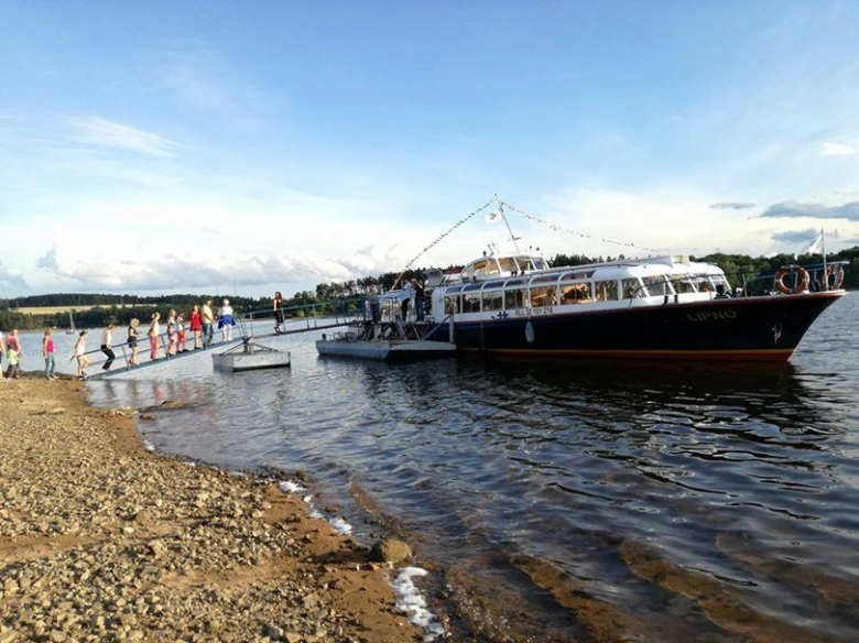 Rodina nastupuje na loď pro výlet po českém jezeře.
