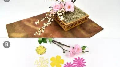 Japonská květinová aranžmá ikebana s růžovými květy a větvemi na hnědém podkladu.