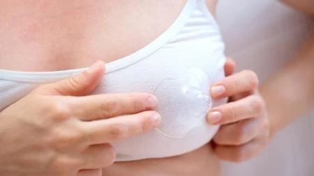 Žena drží menstruační tampon nebo disk na prsou.