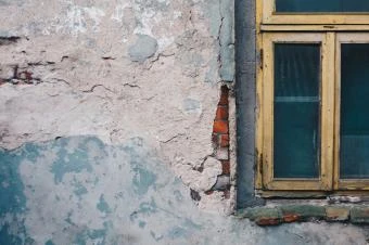 Zvětralá zdi s oknem v pozadí.