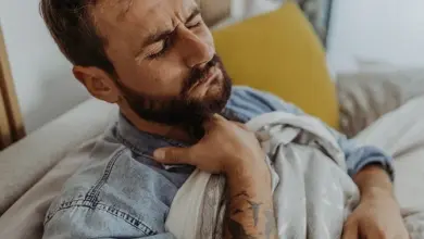 Muž leží v posteli s bolestí při kašli.