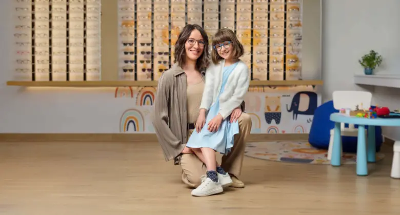 Žena s dcerou v brýlích u výlohy koptiků