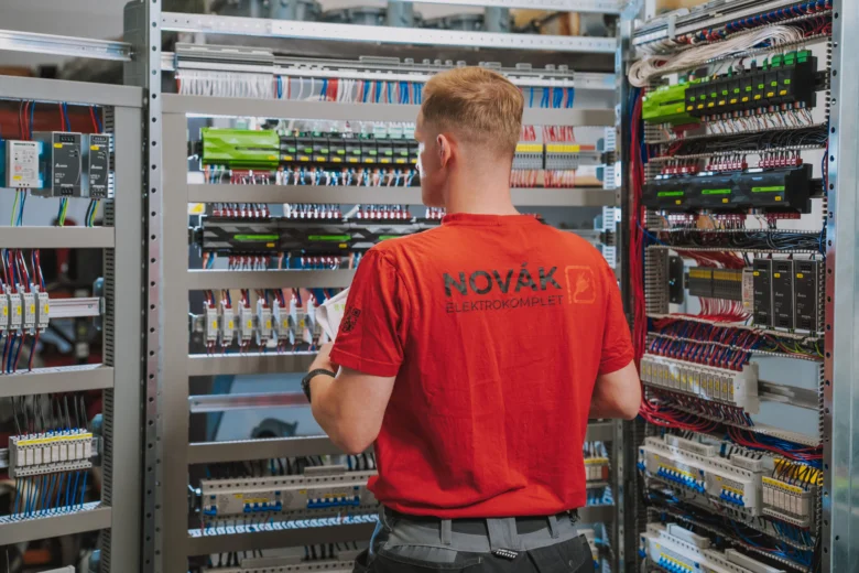 Elektrikář zapojuje rozvaděč s dráty a jističi.