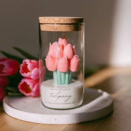 Růžová svíčka ve tvaru tulipánku v skleněné nádobce.