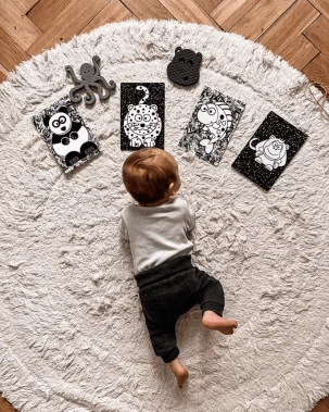 Béba leží na bílém koberci s černobílými obrázky pro klid.