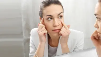 Žena se dívá do zrcadla na svou pleť.