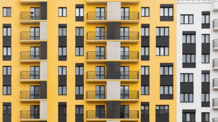 Moderní žlutá provětrávaná fasáda s balkony na bytovém domě.