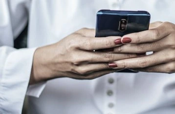 Ruce drží chytrý telefon, nikoliv porodní kontrakce.