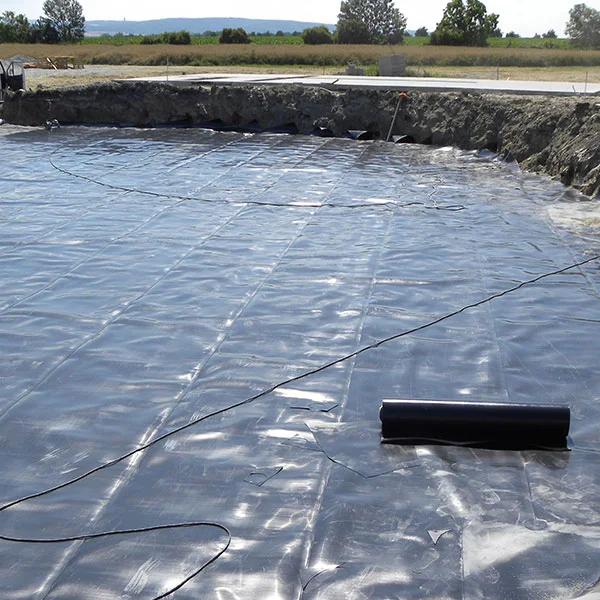 Instalace černé fólie z HDPE na stavbě pro hydroizolaci.