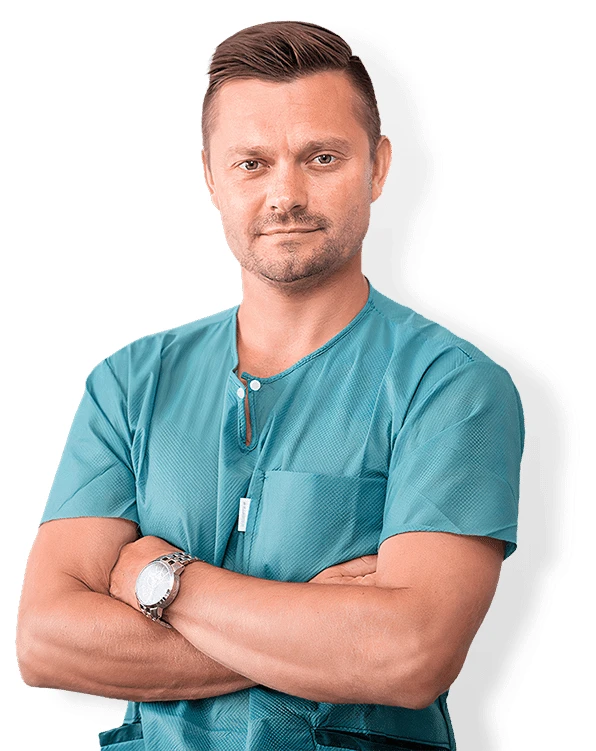 Muž v lékařském oblečení s kříženýma rukama.