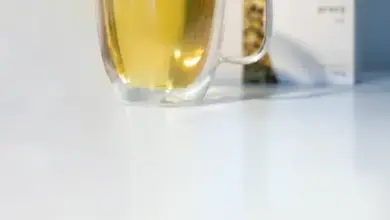 Sklenička s žlutým nápojem vedle balení semen.