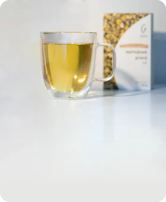 Sklenička s žlutým nápojem vedle balení semen.