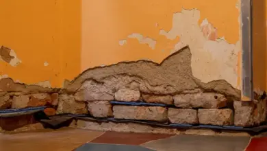 Poškozený roh zeď s odlupující se omítkou před rekonstrukcí.