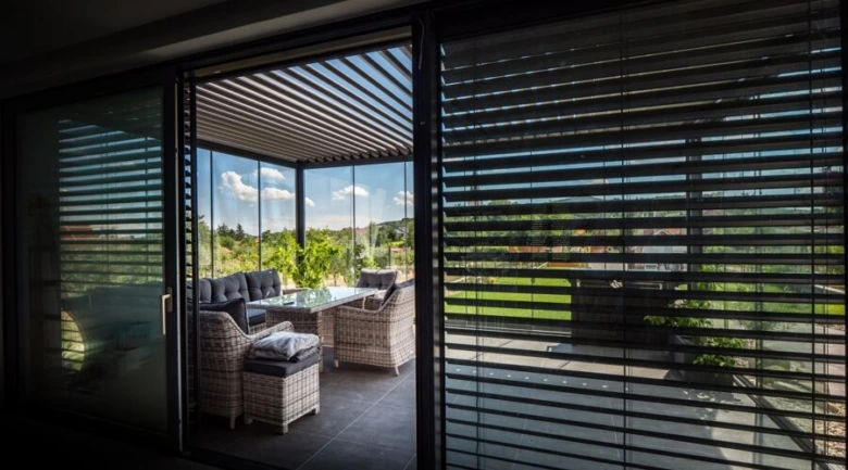 Moderní balkon s roletami na skleněných oknech.