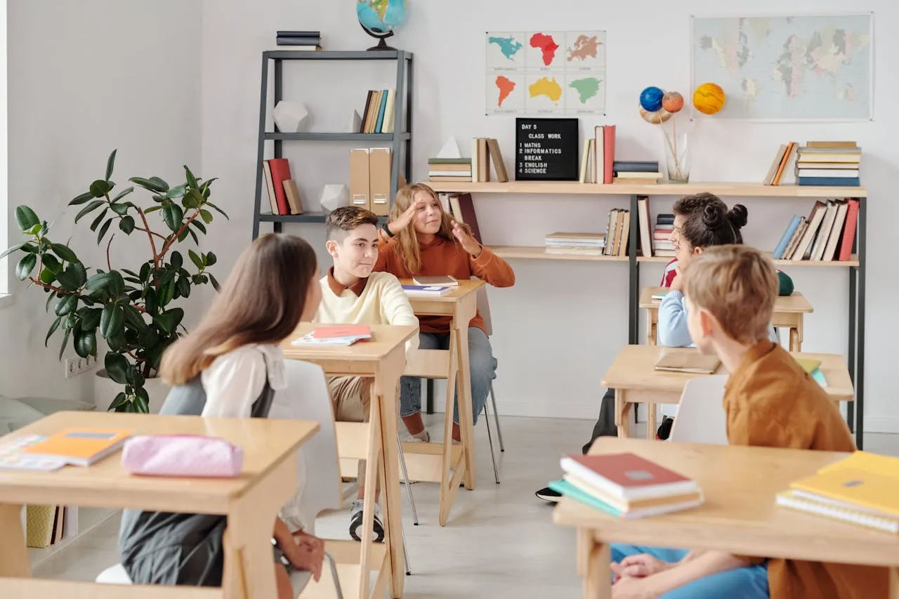 Skupina žáků sedících u desek v jasném školním prostředí.