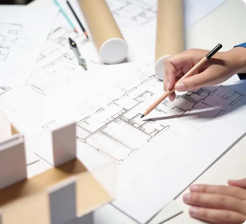 Architektura kreslí plán bytu s tužkou na stolu.