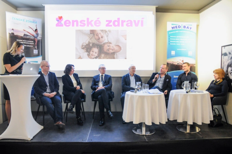Panelová diskuse na téma ženského zdraví s prezentací v pozadí.