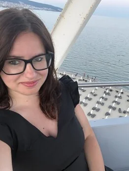 Žena v brýlích na balkóně s výhledem na moře.