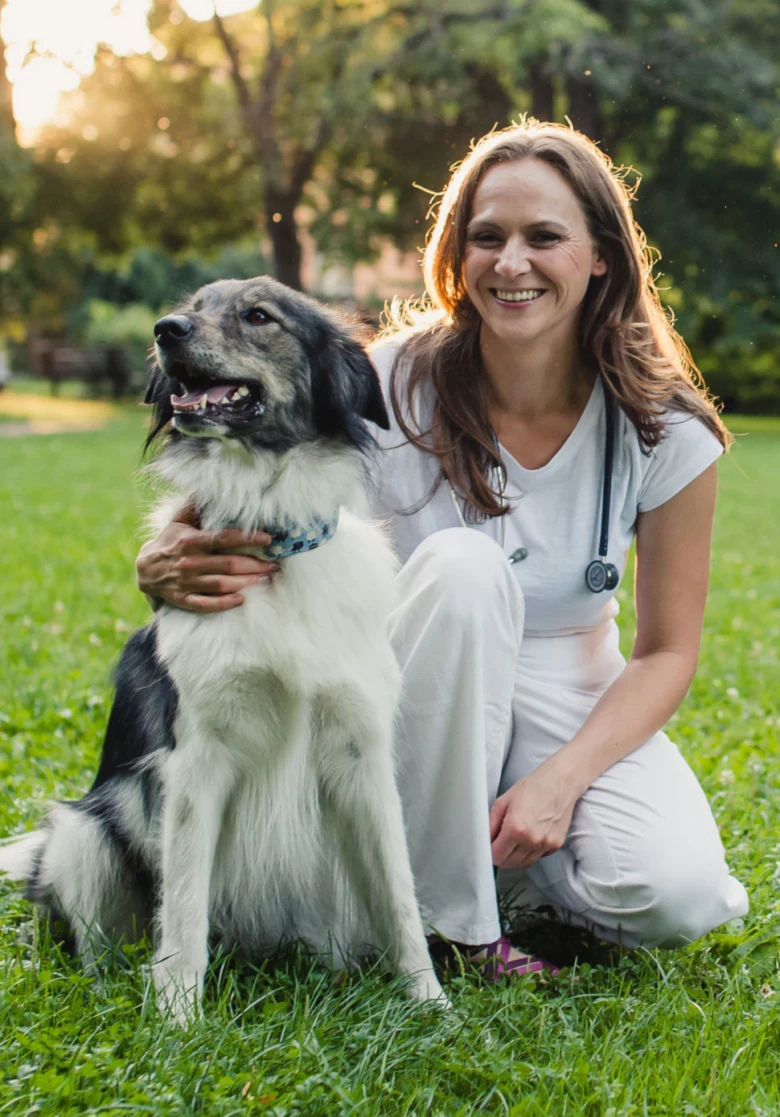 Veterinářka s psem na trávníku v parku.