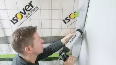 Muž těsní spoji mezi izolací na soklu pomocí pistole.