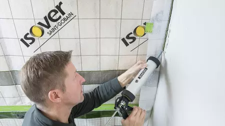 Muž lemuje izolační desku na provětrávanou fasádu.