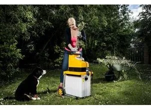 Žena s zahradním strojem a psem na trávníku.