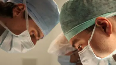Dva lékaři v operačním sále se soustředěně dívají dolů.