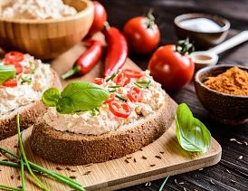 Dva plátky s tofu, rajčaty, bazalkou a chilli na dřevěném podnose.