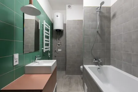 Moderní koupelna s vanou, umyvadlem a zelenými dlaždicemi.
