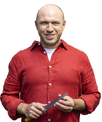 Muž v červené košili drží nůž, příprava jídla.