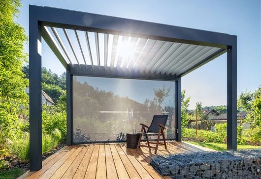 Moderní pergola s bílou clonou na dřevěné terase.