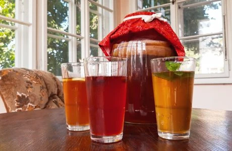 Sklenice s nápoji před velkou sklenicí v kuchyňském okně.