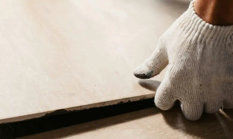 Ruka v rukavici pokládá dlaždicový podlahový panel.
