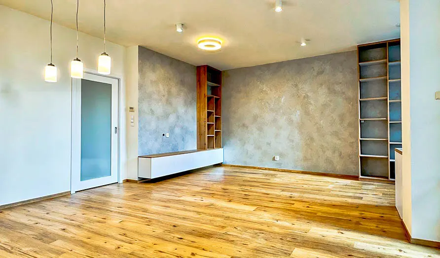 Přestavěná místnost s renovovanými dřevěnými podlahami a moderním designem.