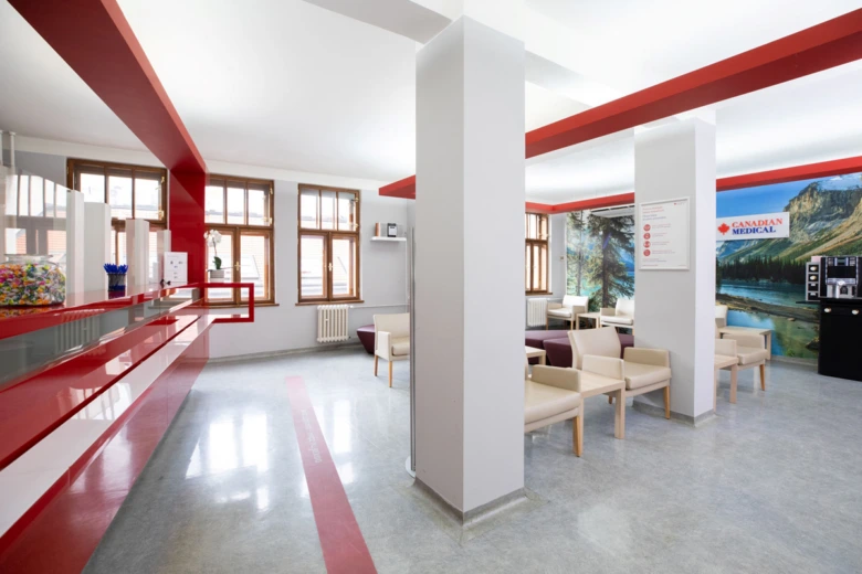 Modern interiér čekárny v lékařské ordinaci s červenými prvky.