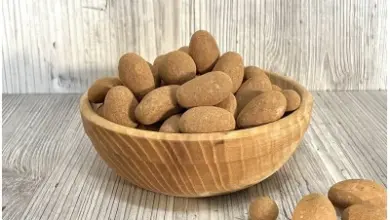 Dřevo talíř s oříšky na světlém dřevěném povrchu.