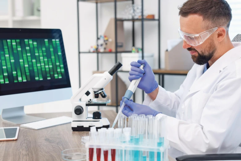 Vědec v laboratoři pracuje s mikroskopem a zkumavkami.